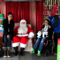 Tylia Flores sits in her wheelchair next to Santa Claus, with other relatives nearby.