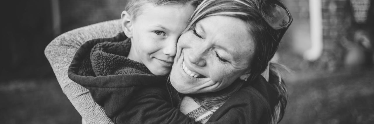 Why ‘Adverse Childhood Experiences’ Can Affect Mental and Physical Health black and white photo of mother hugging son or woman hugging child with the boy looking into camera
