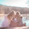 3 women sitting on a dock hugging each other