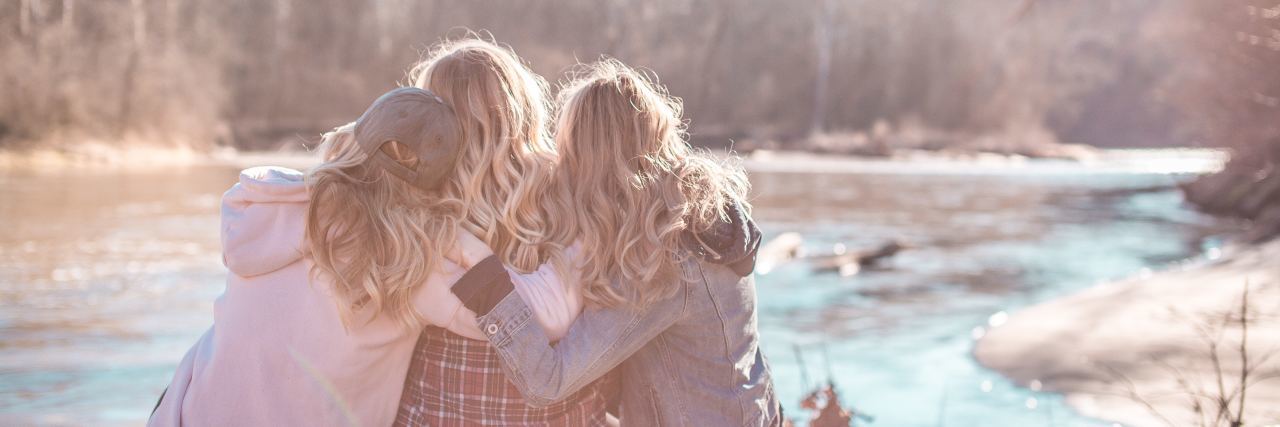 10 Ways to Comfort Someone Grieving During the Holidays 3 women sitting on a dock hugging each other