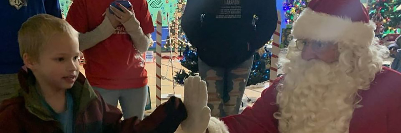 What Disability Inclusion at Christmas Looks Like David giving a high 5 to Santa Claus.