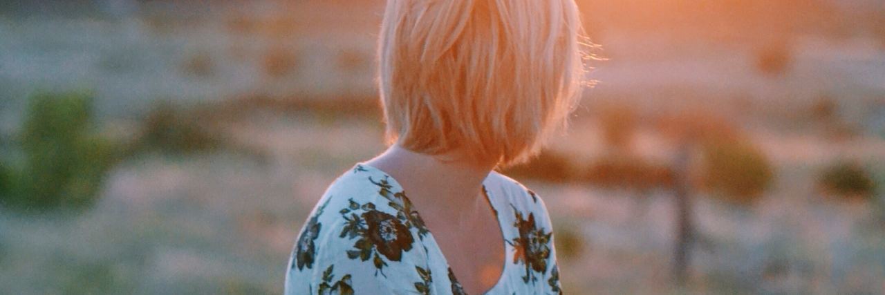 Ideas for Coping With Trauma in the New Year photo of woman sitting in field watching sun in distance with hands on her lap