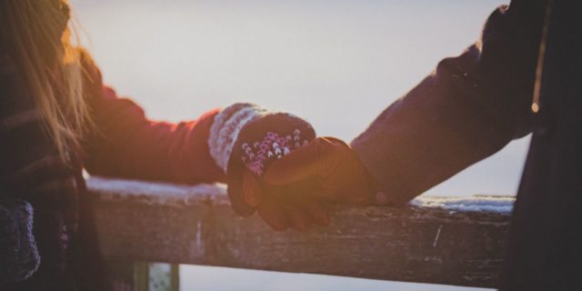 The Best Gift to Give If Shopping Is Hard With a Chronic Illness 2 hands with gloves on holding each other resting on a wooden ledge on a snowy day