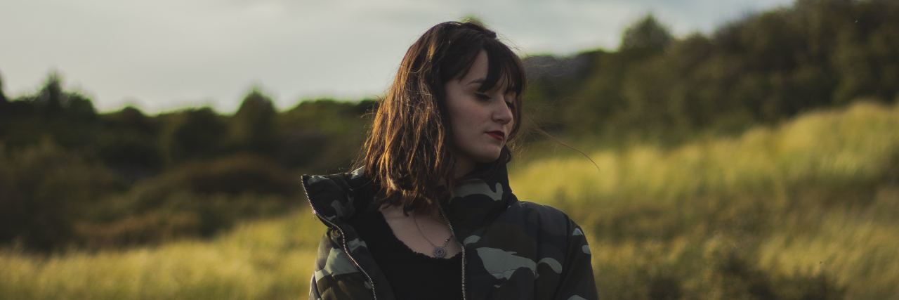 When Your Medication for Depression and Anxiety Stop Working woman in a field wearing a black sports bra and camo jacket looking sideways