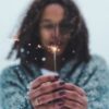 photo of young woman holding sparkler in snow