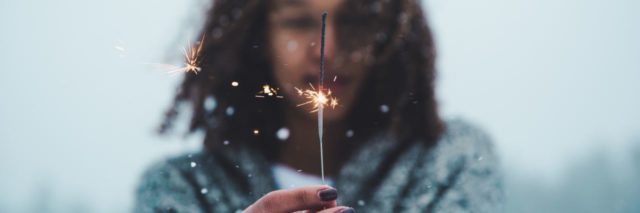 photo of young woman holding sparkler in snow