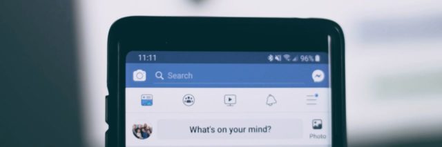 close up photo of phone displaying Facebook top banner with "what's on your mind" written in text box