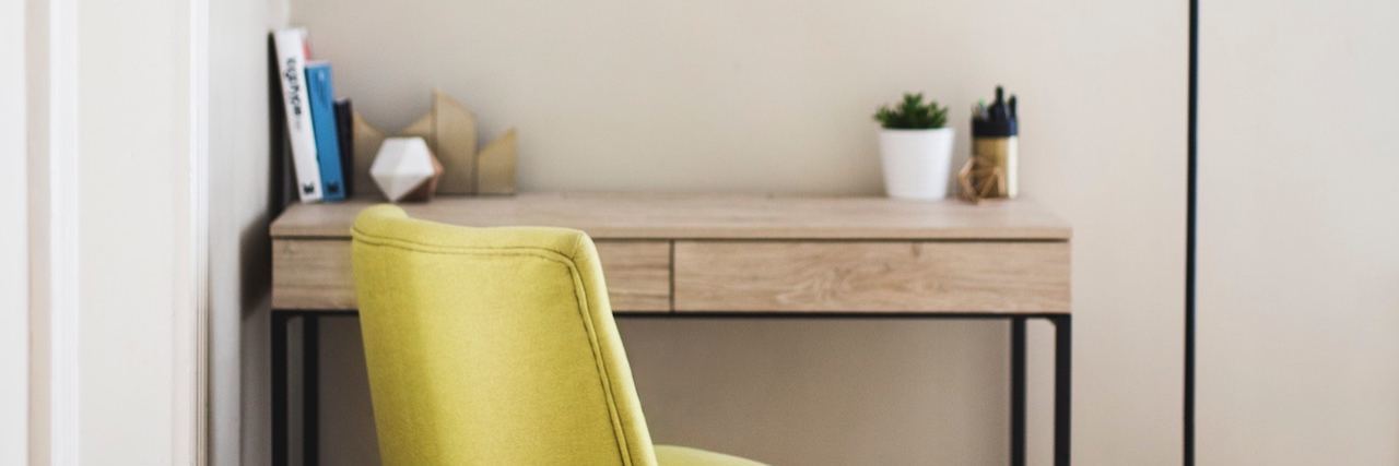 Remote Jobs for People With Disabilities and Chronic Illnesses Corner office with a wooden desk, yellow padded chair and floor lamp