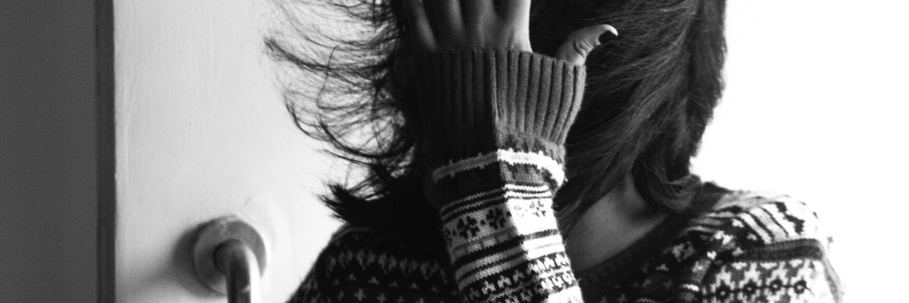 When Using Medical Marijuana for Migraine Became an Addiction black and white photo of woman's hair being blown in wind in front of door, while she covers her face