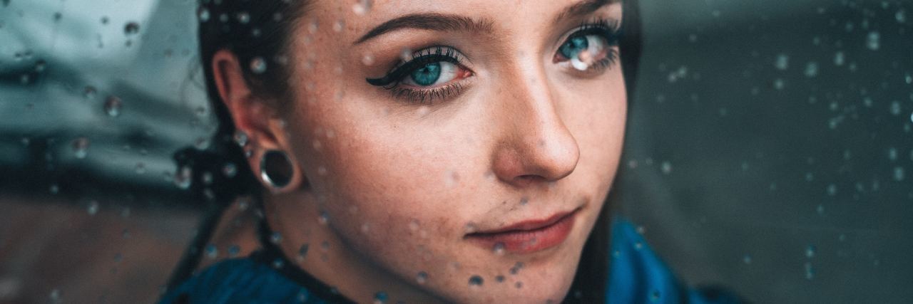 How to Get Through the New Year With Depression photo of woman looking into camera through rainy window