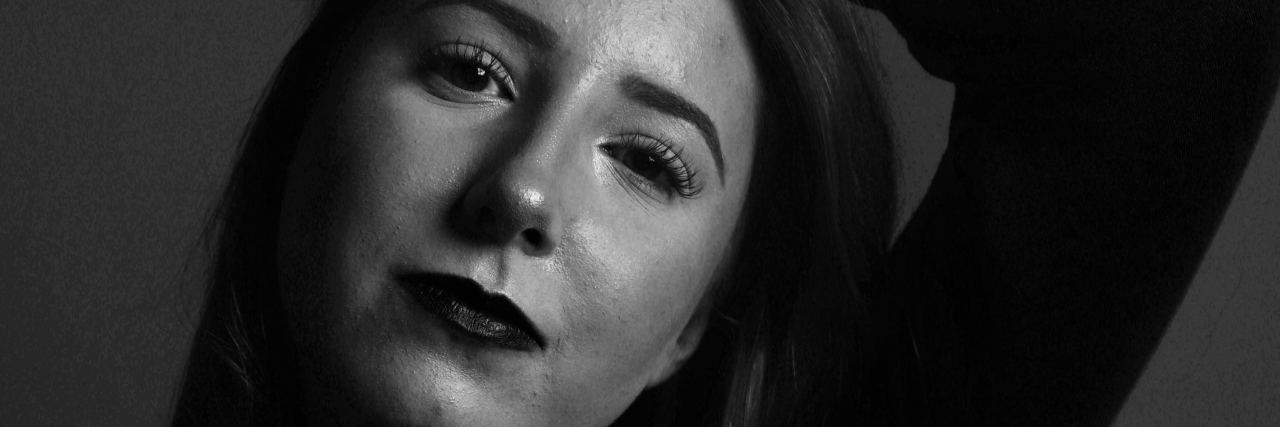 Coping With Self-Doubt With Depression and Anxiety black and white photo of woman looking into camera, arm raised above her head and resting on her hair, looking into camera