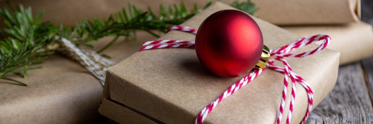 brown paper packages wrapped in red and white string with an ornament on top and garland around