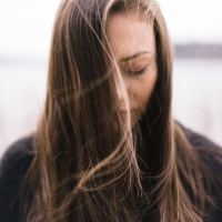 close up photo of young woman with eyes closed and hair partially hanging in front of face