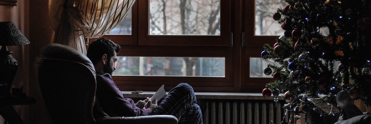 7 Survival Tips for Those With Parkinson's Over the Holidays Man sitting alone next to a Christmas tree