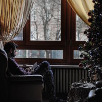 Man sitting alone next to a Christmas tree
