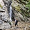 Person hiking near small waterfall.