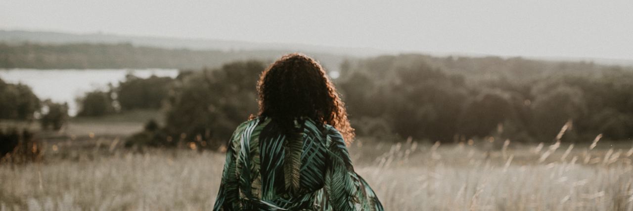 My Experience With Self-Harm and Learning to Care for Myself back of a woman in a green and white dress in a field looking ahead