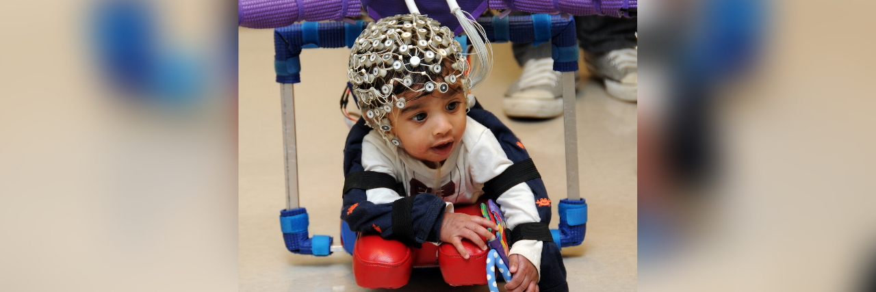 Child with cerebral palsy using a "smart onesie" a complex device with brain and body sensors.