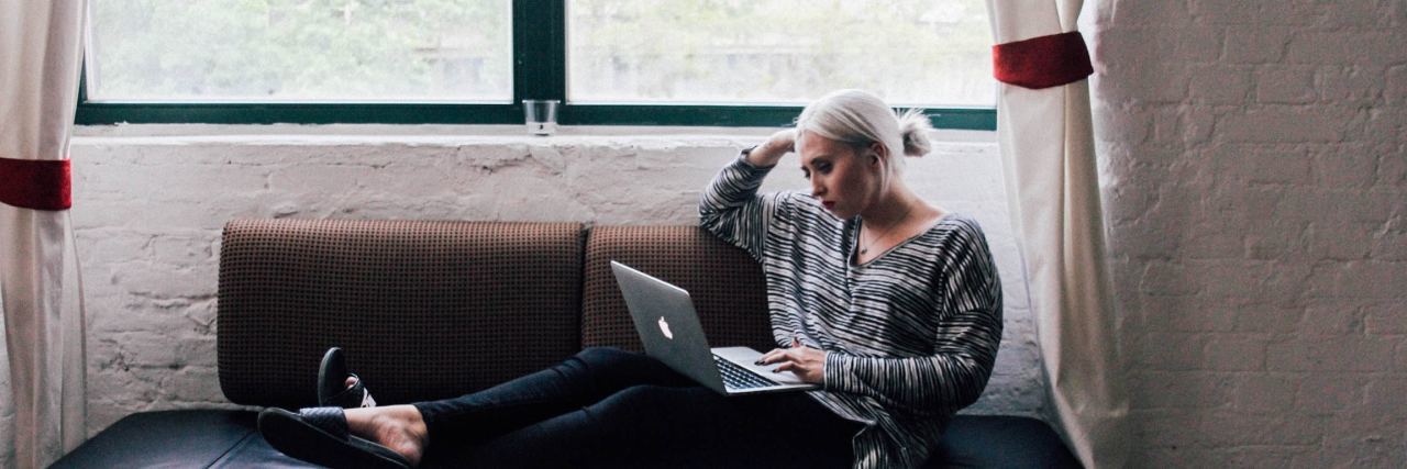 Anxiety Makes Online Friendships Easier but They're Not as Fulfilling blonde haired woman laying on a couch on her computer