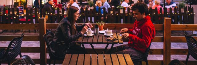 photo of couple on a dinner date with bright restaurant lights behind them