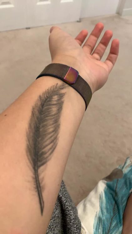 Chelsea shows the viewer a tattoo of a feather. It is located on her arm.