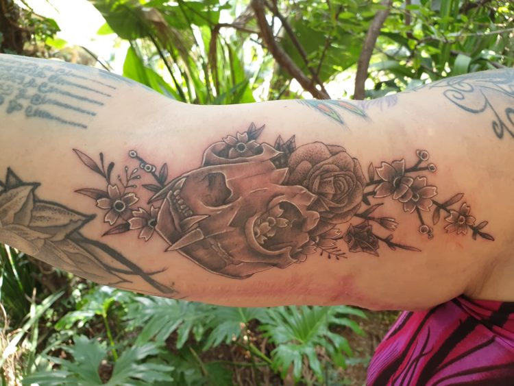 Belinda shows off the tattoo on her arm, which is of the skull of a fanged animal. The skull has pink flowers growing inside.