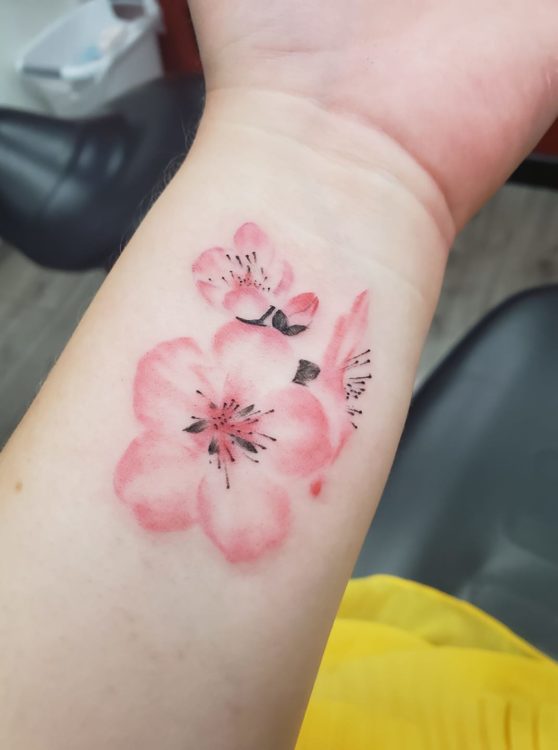 An arm with an almond blossom tattoo.