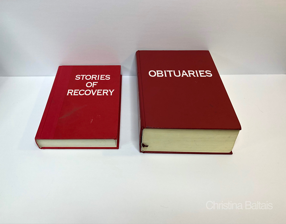 Photo of two red books, one small reading "stories of recovery" and one large reading "obituaries"