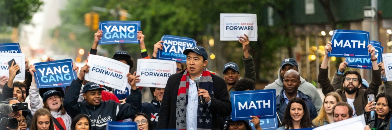 Andrew Yang surrounded by supporters at a rally.