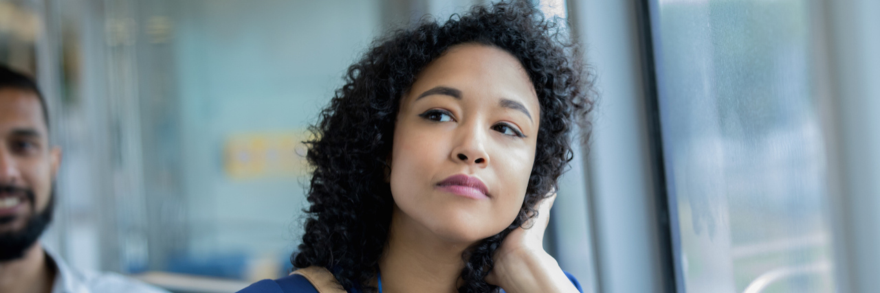 Let's End the Stigma Around Electroconvulsive Therapy Young woman is resting her head in her hand while sitting in train car.