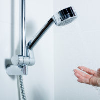 hand reaches towards shower head and water