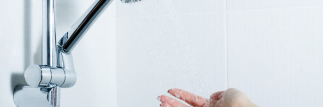 hand reaches towards shower head and water