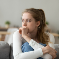 Head shot woman anxious worried woman sitting on couch at home
