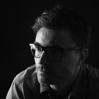 Portrait of a man wearing glasses, in shadow