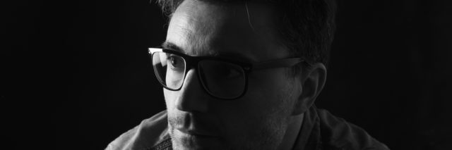 Portrait of a man wearing glasses, in shadow
