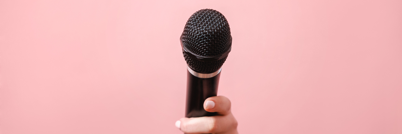 microphone in someone's hand on pink background