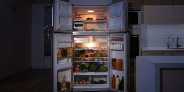 What Hunger Actually Feels Like With Prader-Willi Syndrome Open refrigerator filled with food in kitchen at night
