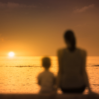 Mother and child sitting together watching the sunset.