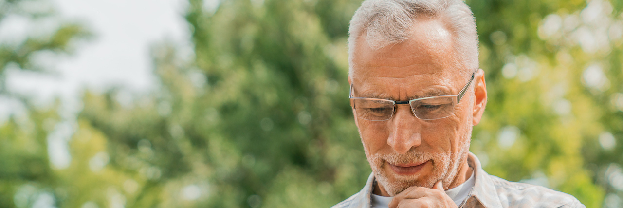 What to Know About the Geriatric Depression Scale Man sitting outside on park bench thoughtfully looking at a tablet