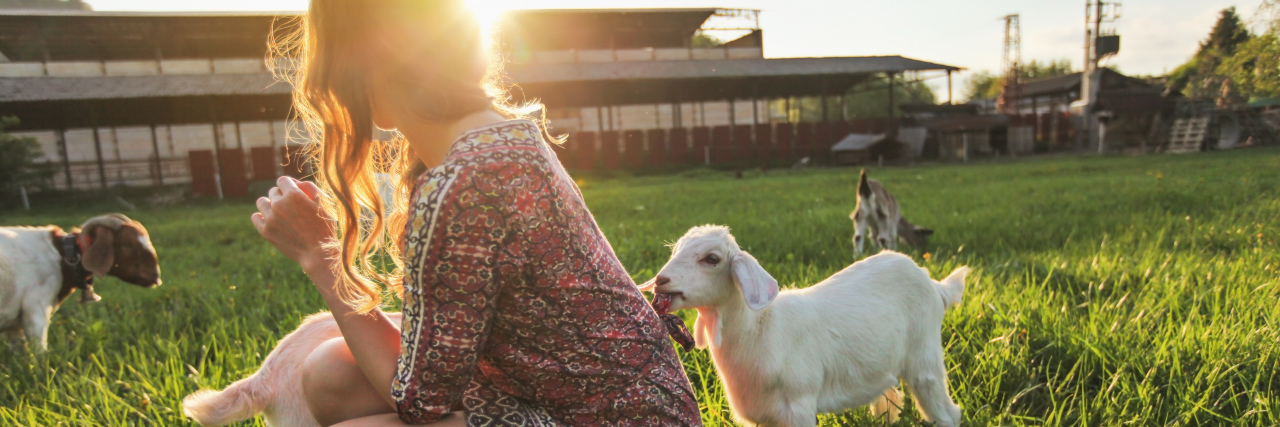 a young woman is playing with a goat