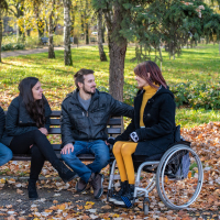 Young disabled woman in a wheelchair with friends in a park.
