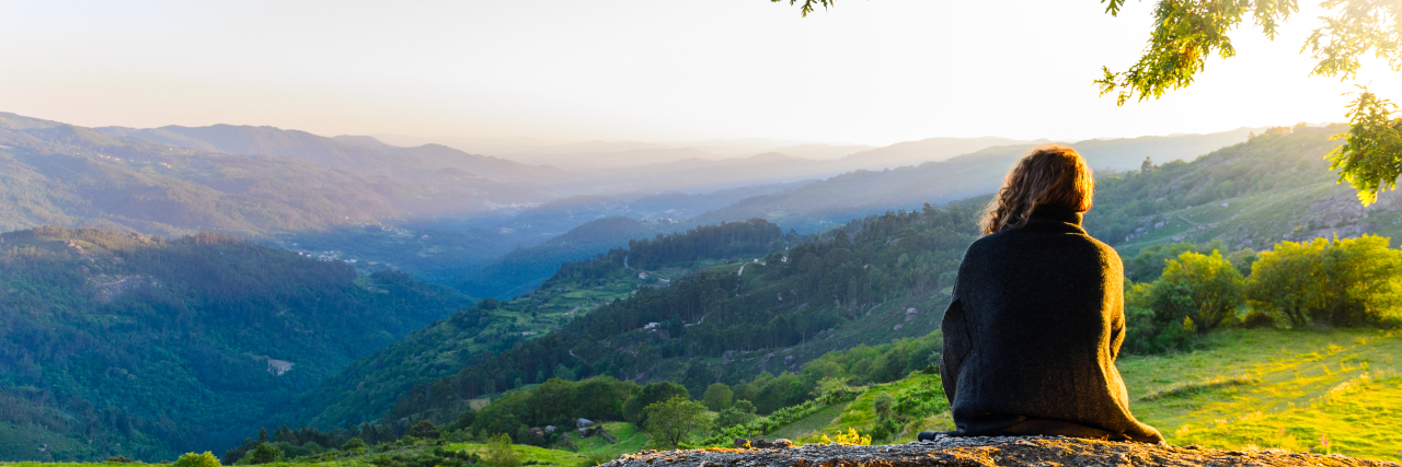 What Positive Thinking Means in My Life With Chronic Illness Woman looking towards mountains at sunset.