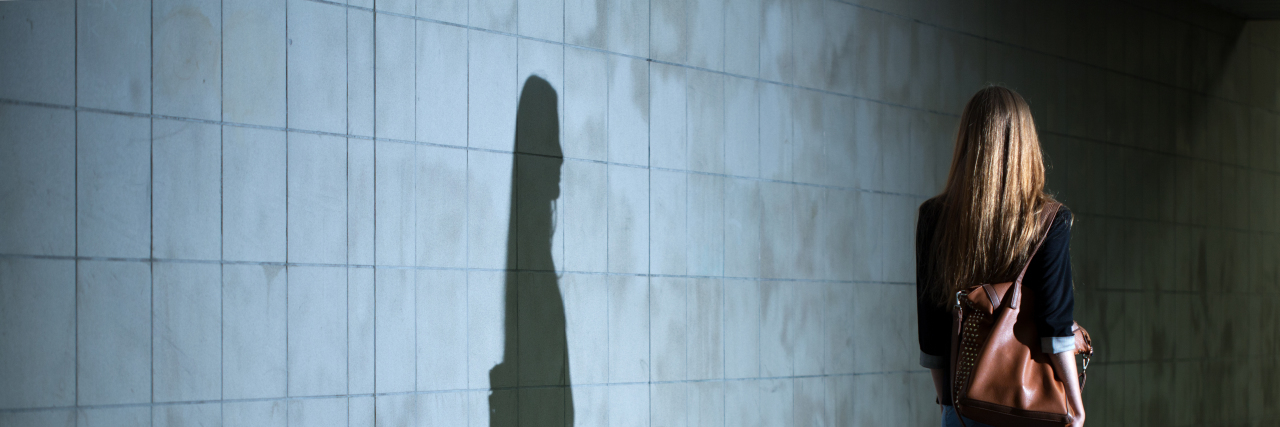 Unconscious Bias Against People on the Autism Spectrum Woman walking, her shadow cast on the wall.