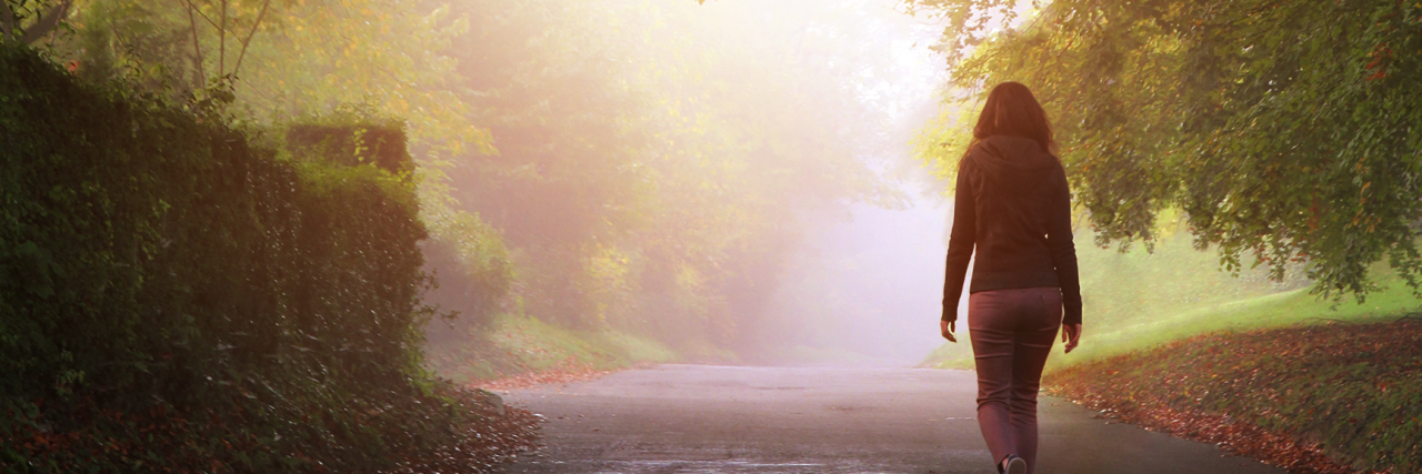 Myalgic Encephalomyelitis and Short-Term Memory Loss A woman walks towards the light on a misty day on a country road.