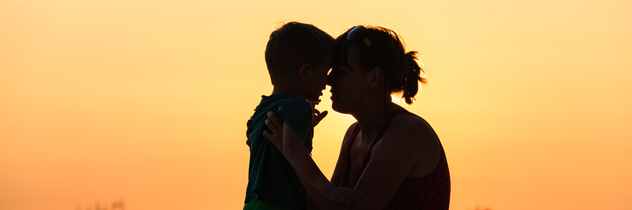 Happy mother and son at sunset on beach.