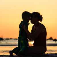 Happy mother and son at sunset on beach.