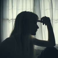 silhouette of a woman sitting in bed by a window thinking