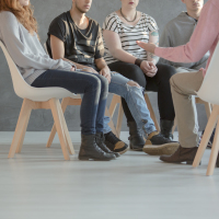 group therapy setting with 4 people sitting in chairs in a circle