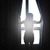 Woman opening the curtains of a window in the morning
