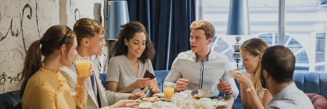 Living With Central Auditory Processing Disorder Group of friends eating breakfast and socializing in a restaurant.